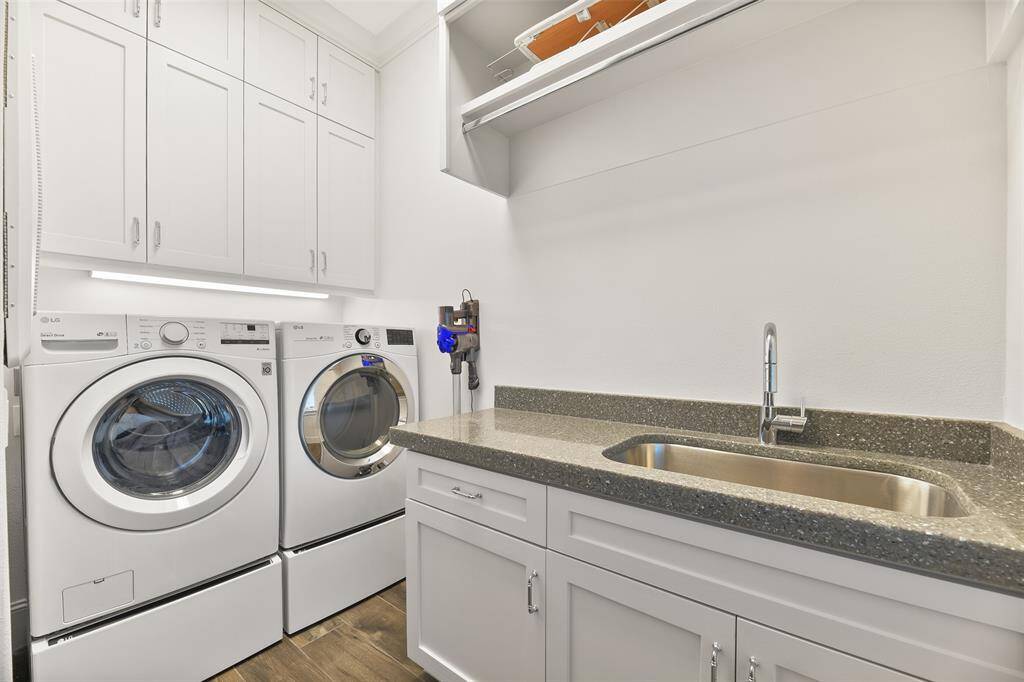 One of two laundry rooms in this home, this space offers a full countertop, sink, custom-built cabinets, and a convenient drying rack. With ample storage options, laundry day is transformed into an organized and effortless experience.