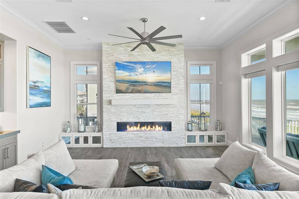This home is the ultimate luxury beach home! Flooded with natural light, this inviting living room boasts custom built-ins for decor or extra window-seating and expansive windows that offer stunning views of the Gulf. Enjoy the perfect blend of modern convenience and breathtaking coastal scenery from every angle.