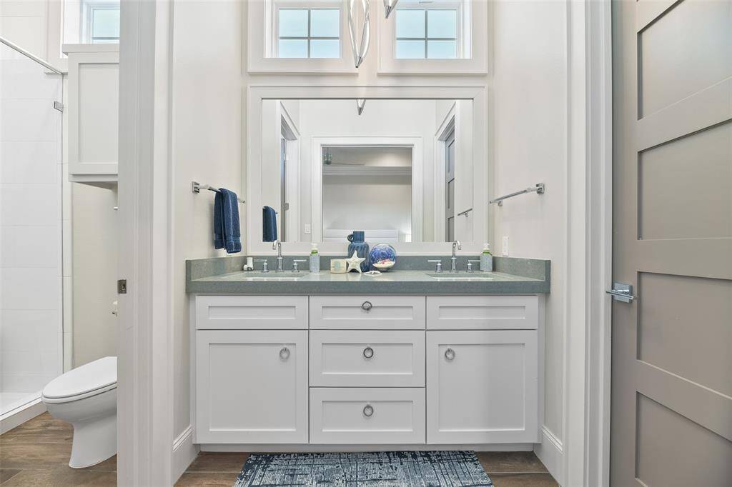 The beautifully designed sink and countertop serve as a stylish divider between the spacious closet and the full bathroom, offering both functionality and elegance in this thoughtfully planned space.