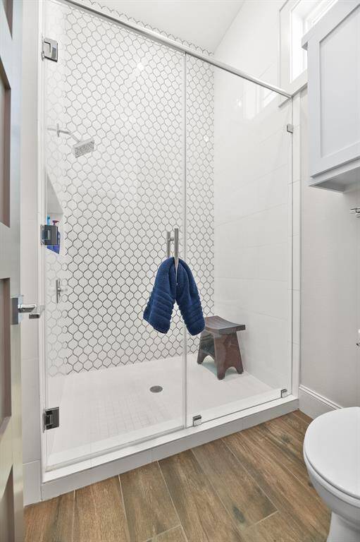 The ensuite bathroom features a full-sized shower adorned with stunning custom tile work, offering a luxurious and inviting space for ultimate relaxation.