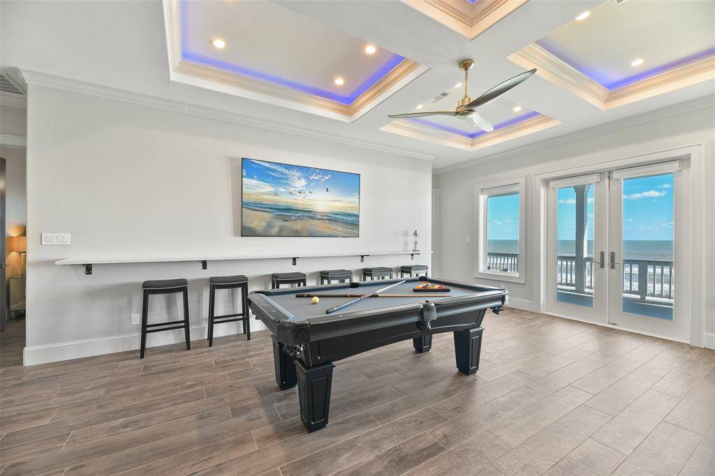 The game room is fully equipped for entertaining, featuring bar-style seating and a massive TV, perfect for hosting gatherings and watching the big game in style.