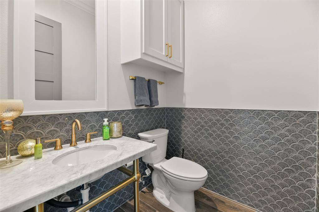 This upstairs half bath, located just off the game room, features a sleek trench-style sink and eye-catching custom designer tile work, adding a touch of luxury and style to this entertaining space.