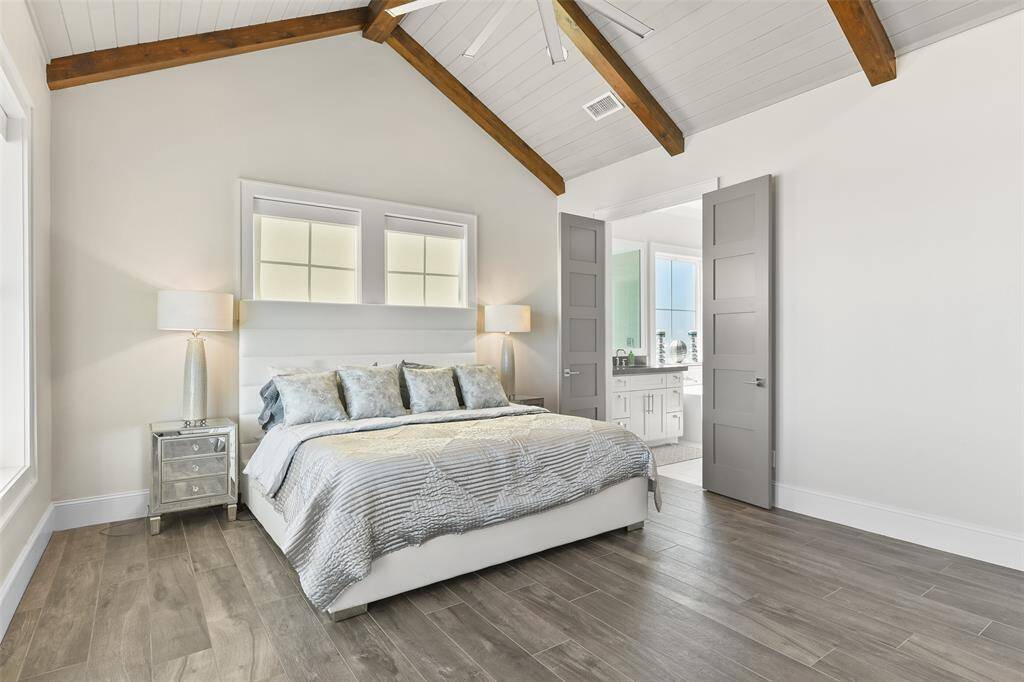 This primary bedroom showcases high-end designer flooring, a stunning wood-beamed ceiling, and abundant natural light. With breathtaking beach views, it offers the perfect blend of luxury and serenity.