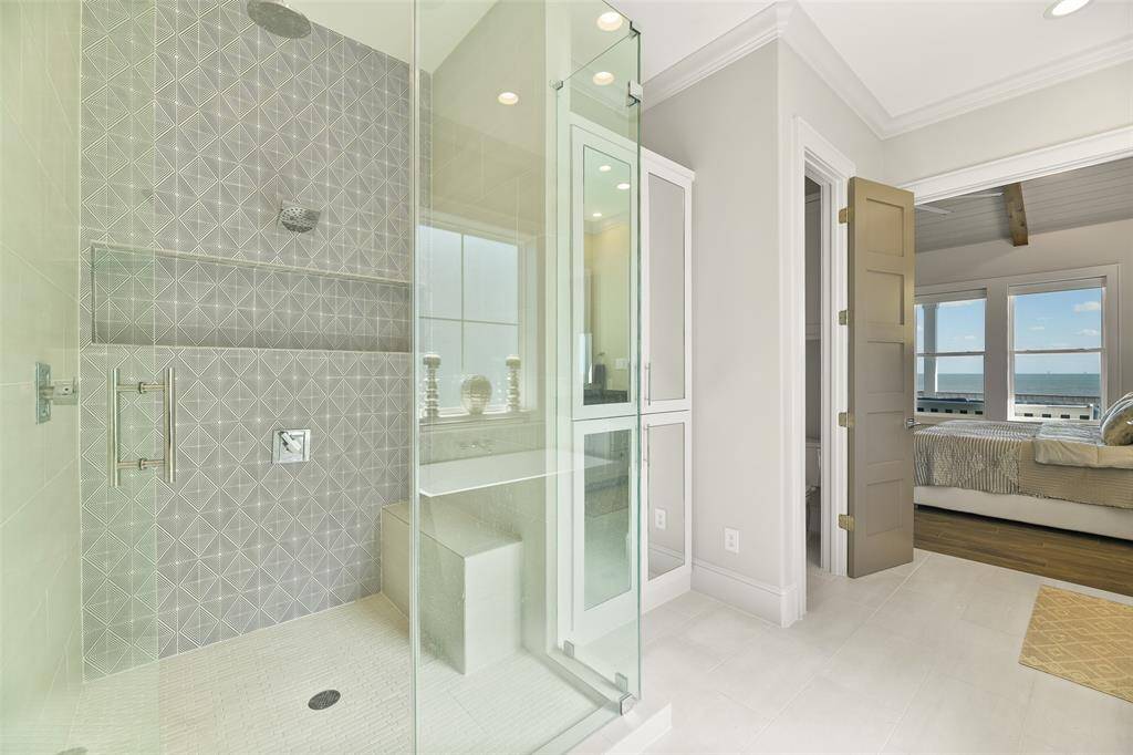 The primary bathroom offers a stunning standing shower with unique, beautiful tile work, dual shower heads including a rainfall feature, and 3/8" frameless glass doors. Thoughtfully designed with built-in soap shelves and a shower seating area, this space blends luxury with functionality. Take a moment to admire the ample storage with a custom-built linen closet and a side water closet for privacy and functionality.