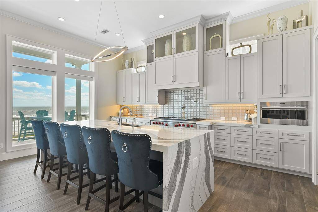 This home is the ultimate luxury beach home! Flooded with natural light, this inviting living room boasts custom built-ins for decor or extra window-seating and expansive windows that offer stunning views of the Gulf. Enjoy the perfect blend of modern convenience and breathtaking coastal scenery from every angle.