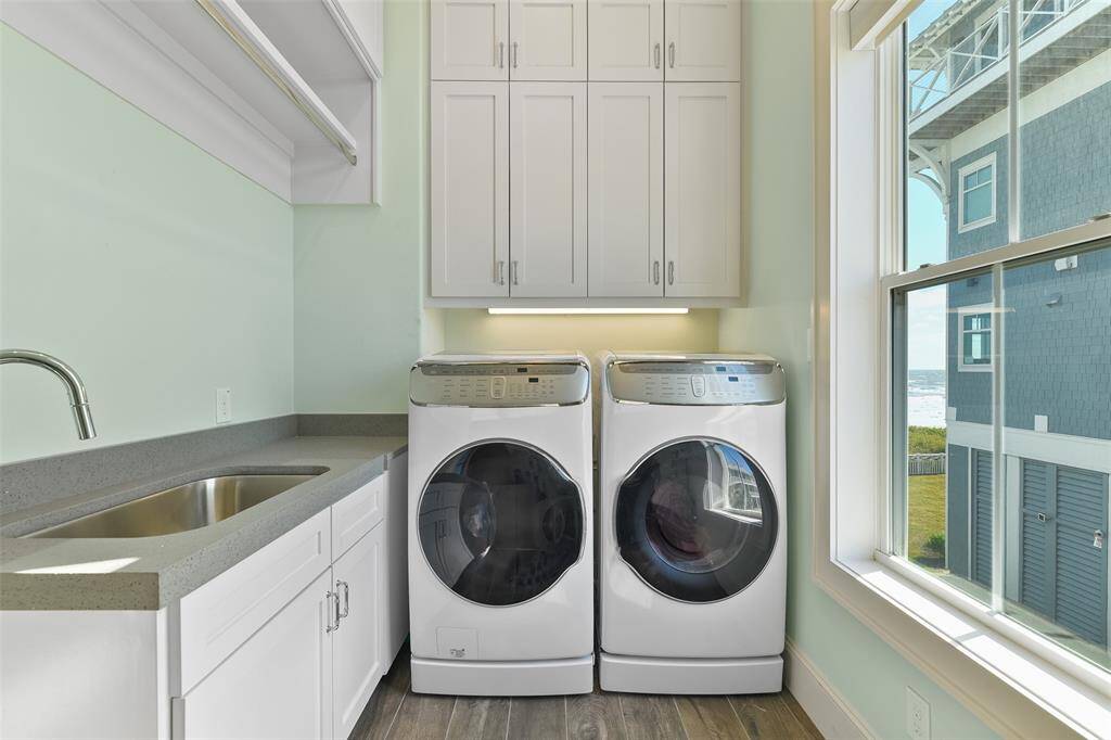 One of the two laundry rooms in this home, this space is fully equipped with a large countertop, sink, custom-built cabinetry, and a handy drying rack. Offering plenty of storage, it makes laundry day both efficient and effortlessly organized.