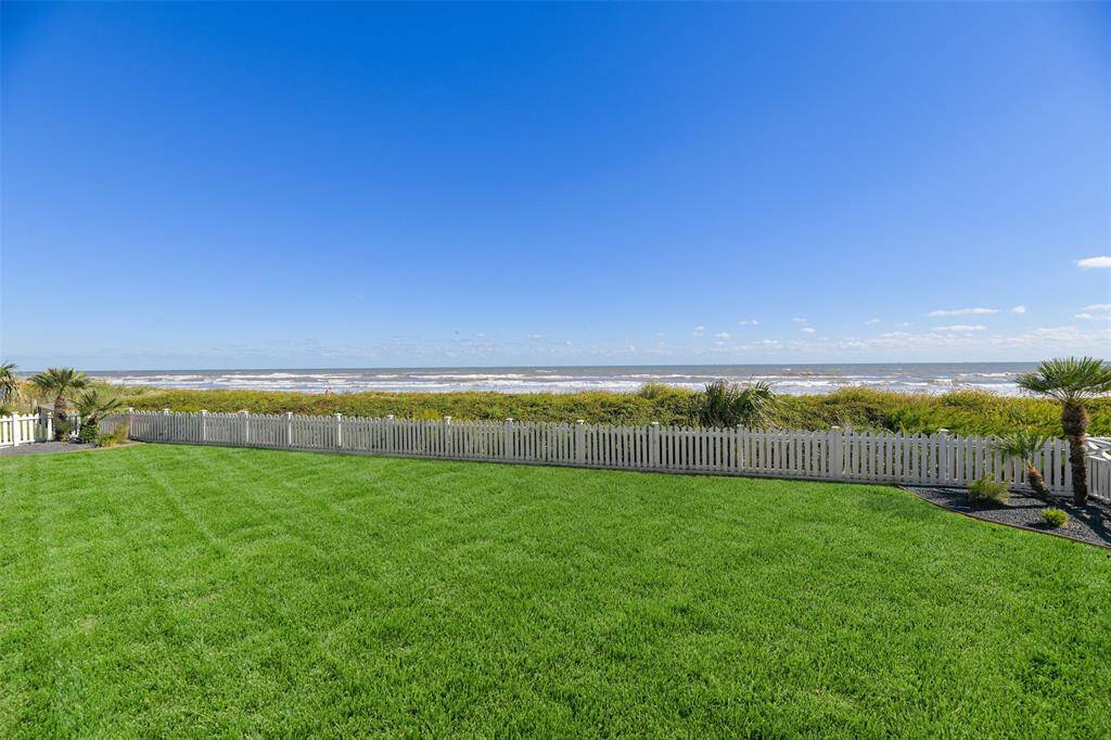 The charming white picket fence encloses a fully fenced backyard with plenty of greenspace, allowing for relaxation and play, all while maintaining uninterrupted, stunning views of the beach.