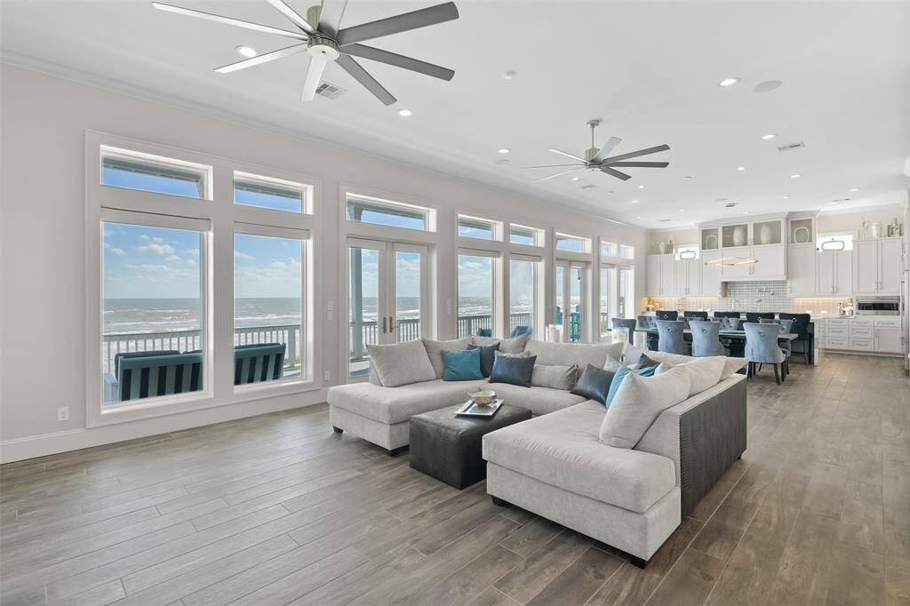 Seamlessly blending indoor and outdoor living, this expansive living room and kitchen open directly to the beachfront back porch with Nuema Impact triple-latch exterior doors with stainless steel hinges. With stunning high-end designer floors and sleek modern fixtures, this space offers luxury and comfort for unforgettable coastal living.