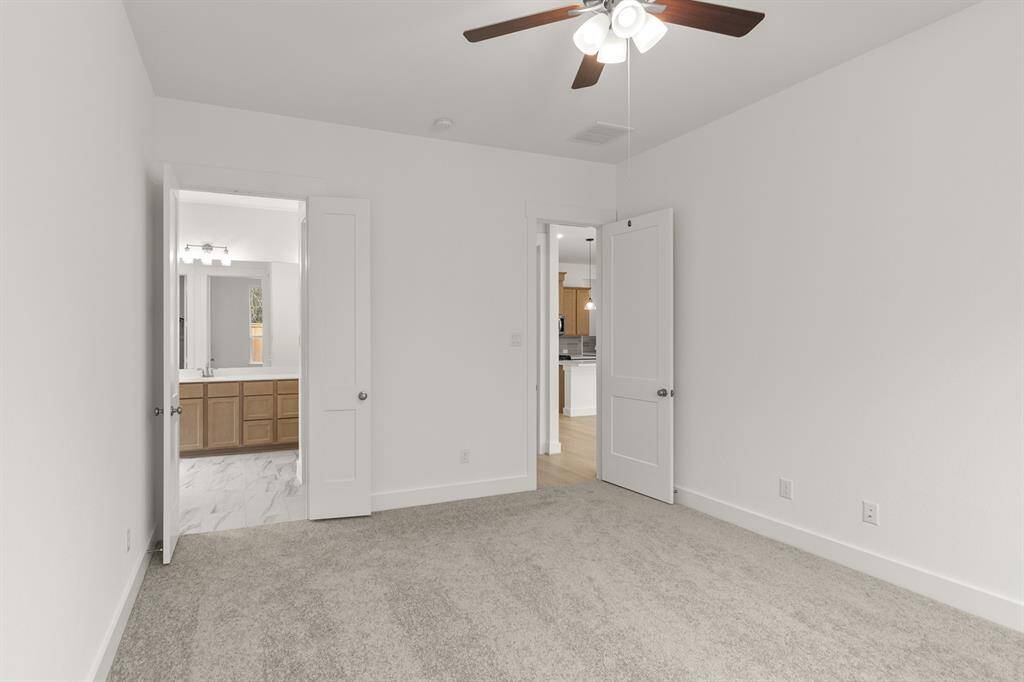 The room flows seamlessly into a luxurious primary bathroom, where a spa-like atmosphere a