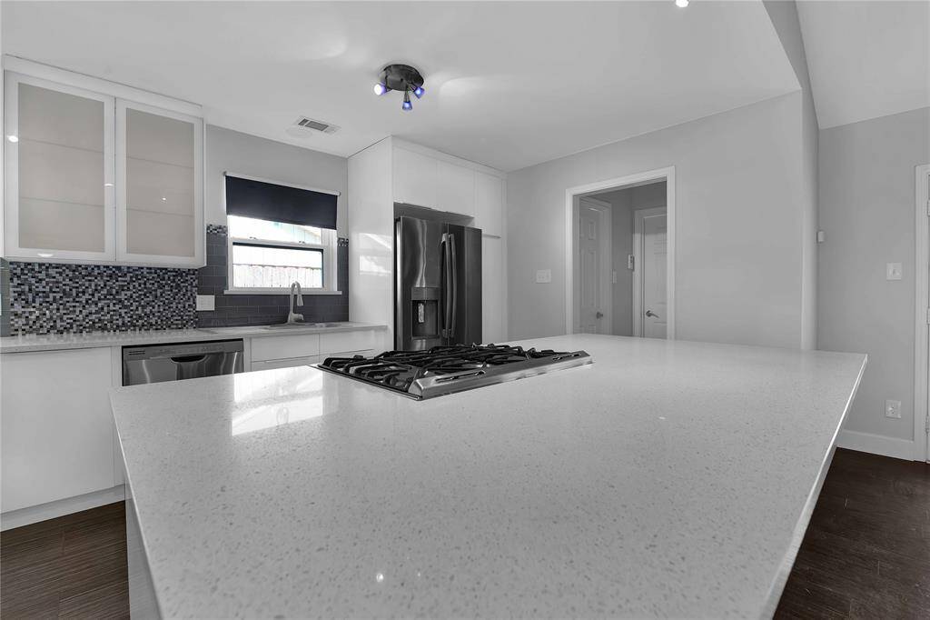 Experience modern elegance with this kitchen's sleek quartz countertops and central island, complete with a high-end gas cooktop for gourmet cooking.