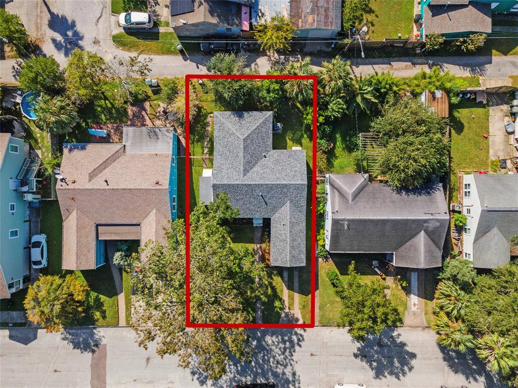 This aerial photo shows a detached single-family home with a spacious backyard, outlined in red, situated in a residential neighborhood with street access and surrounding homes.
