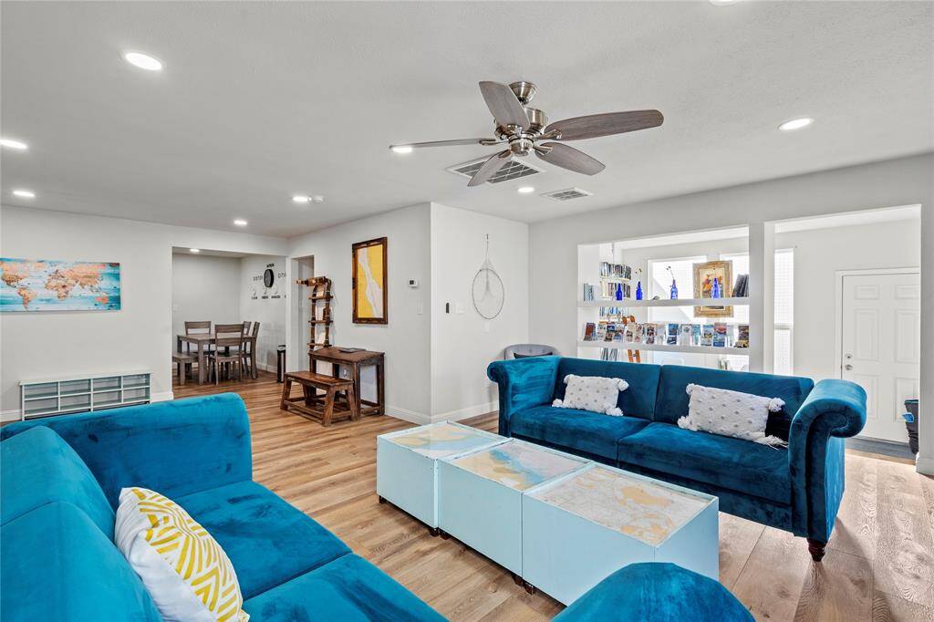 Charming single-story home with a light blue exterior and vibrant yellow door, featuring a neat front lawn with a mature tree, and a welcoming walkway leading to the entrance.