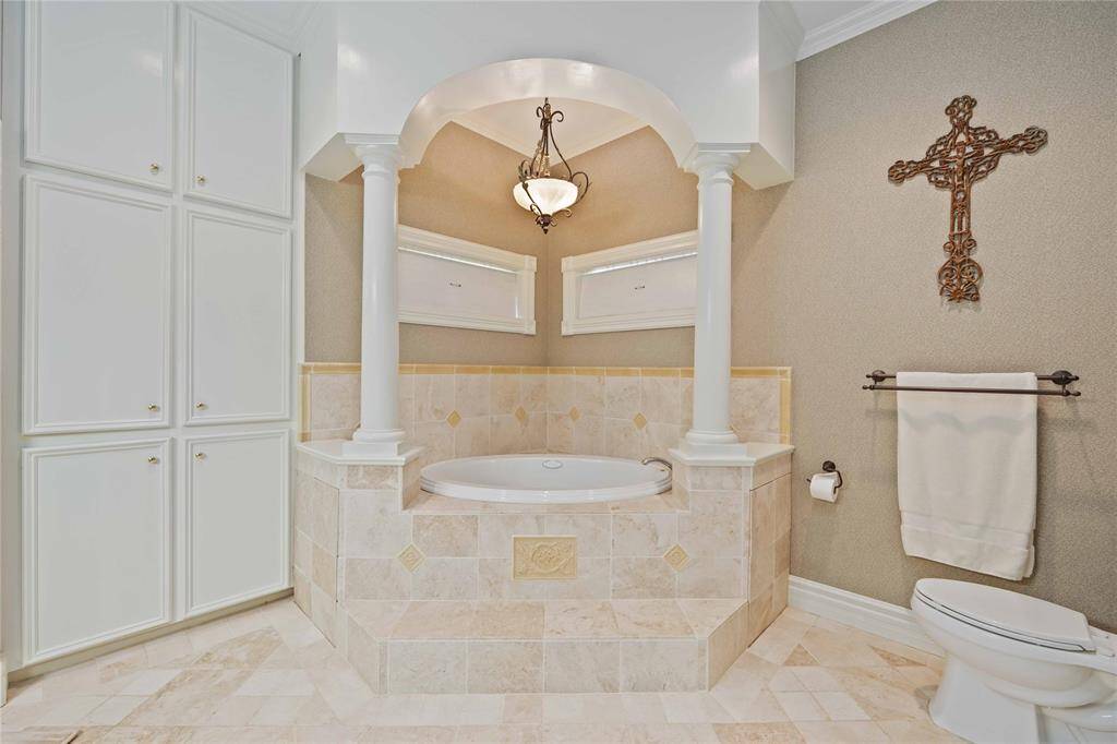 The primary bath offers a separate shower and ornate corner tub, custom built in linen cabinets and an oversized walk in closet.