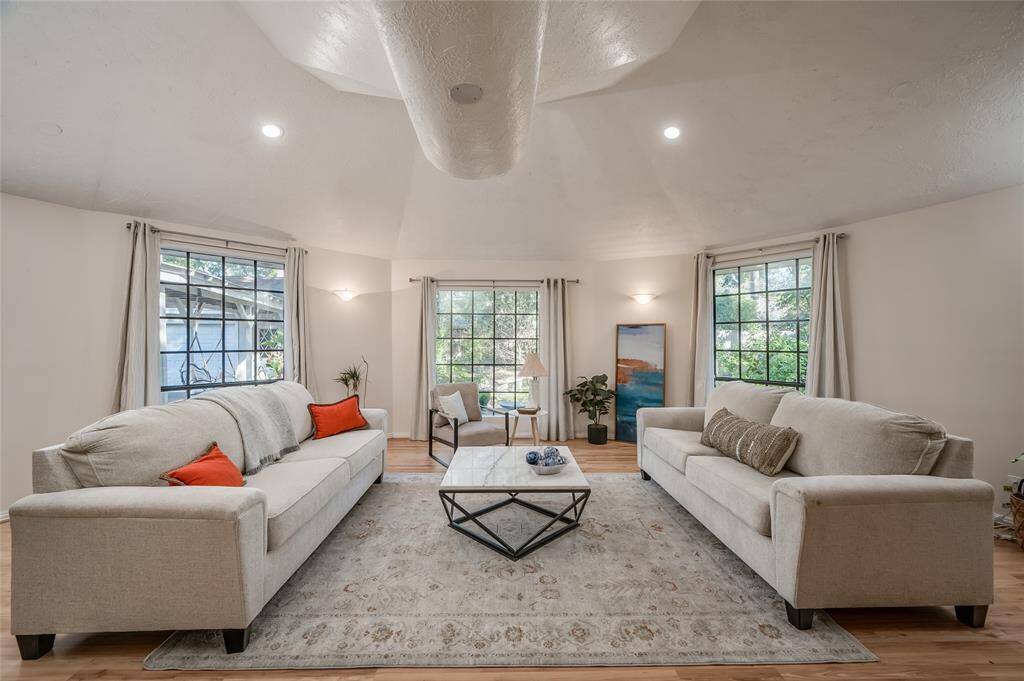 This is a spacious and well-lit living room that was added on by the sellers that offers high ceilings, large windows with ample natural light, and a neutral color scheme that offers a great deal more square footage to the home.