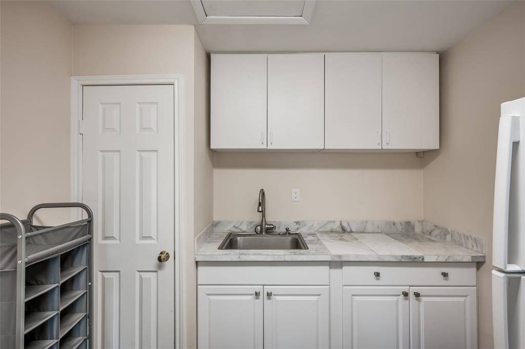 A gem of a find, this oversized utility room has a full sink, loads of cabinetry, space for a fridge/freezer in addition to full sized washer and dryer located to the right of this photo.
