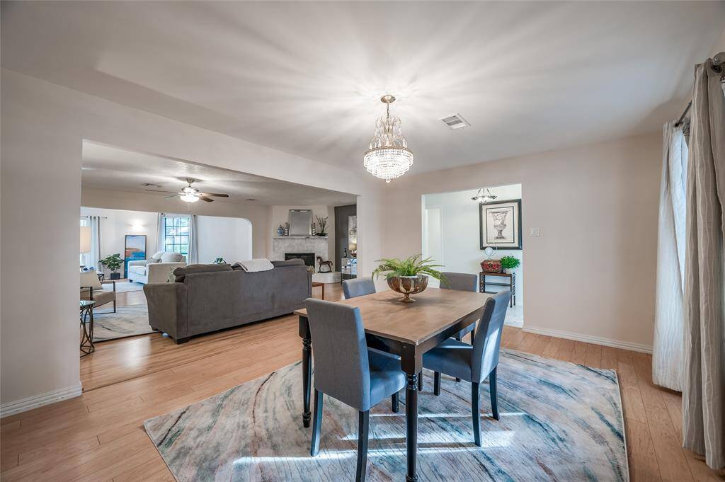 This is a bright, open-concept living space featuring a modern dining area with a chandelier, hard surface flooring, and a seamless transition to the adjacent den and family room, perfect for entertaining and comfortable living.
