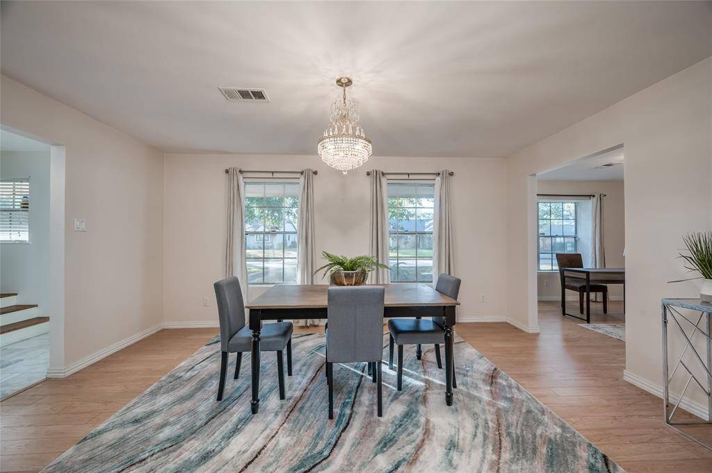 This is a spacious, well-lit flex space featuring a modern chandelier and large windows with window treatments.  It would work beautifully as a home office space, downstairs play room or formal living/library space.