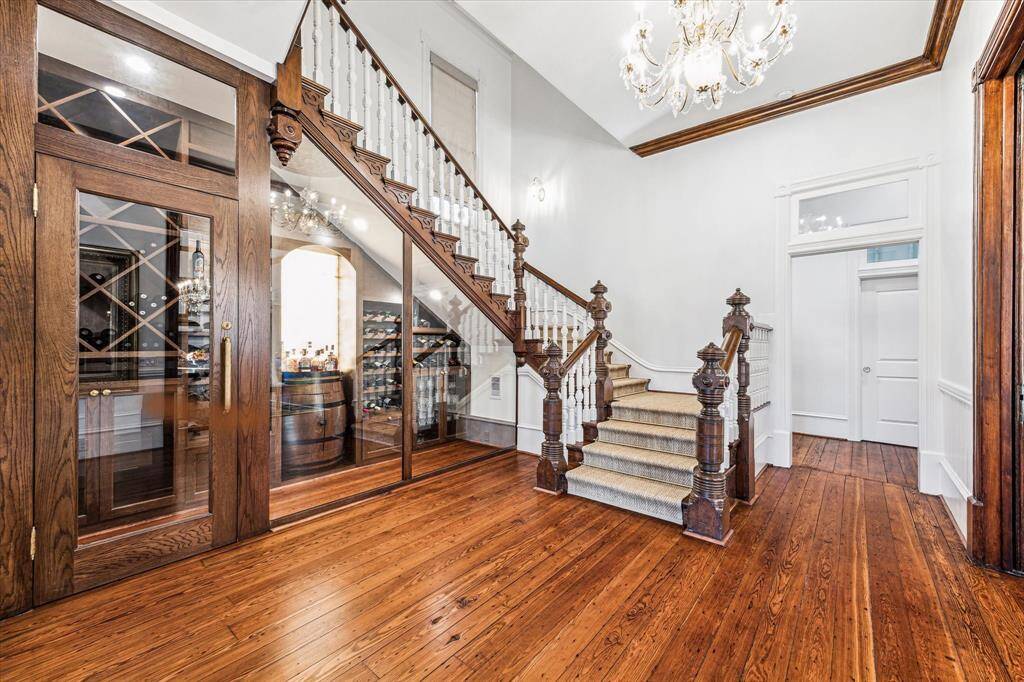 Custom Wine/Whiskey Cellar. Original floors and refinished grand staircase, Seagrass runner with brass stair runner rods. Schonbek crystal chandelier above the grand stair case.