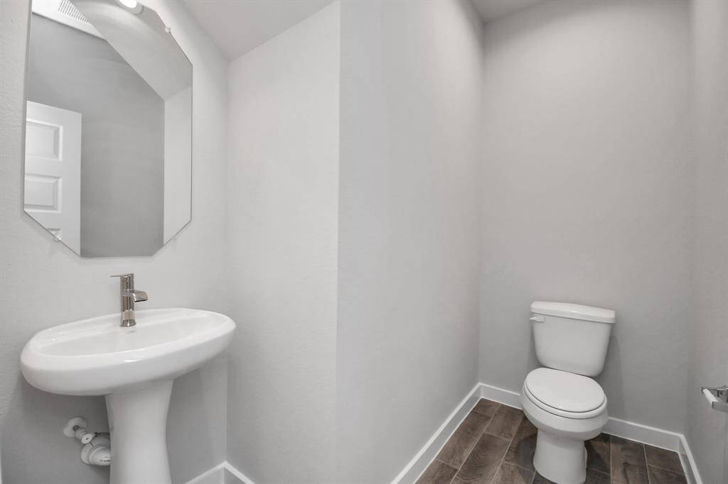 This half bathroom features a stylish pedestal sink, modern hardware, and bright recessed lighting, creating a sleek and inviting space.