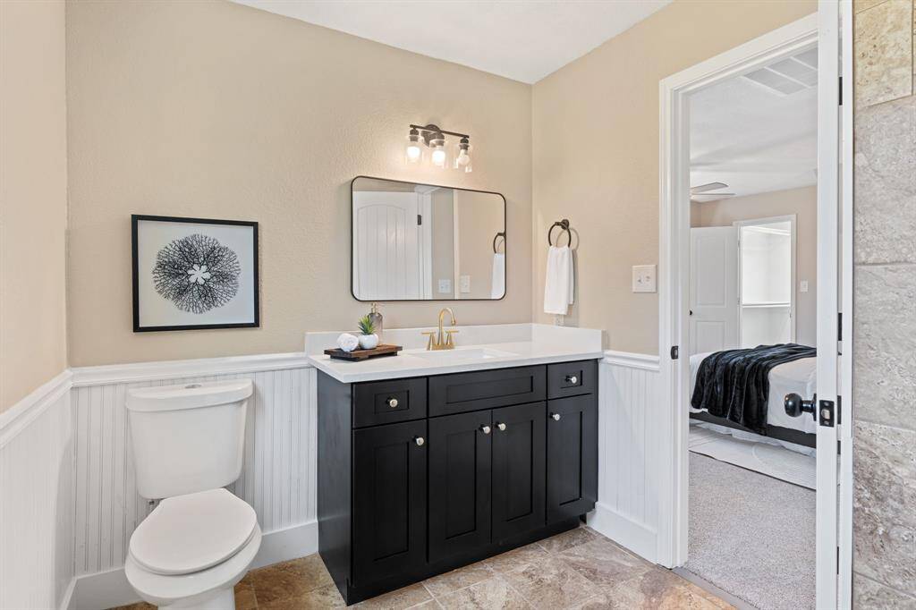 The primary bathroom features dark cabinets, white counters, tile floors, and a large window.