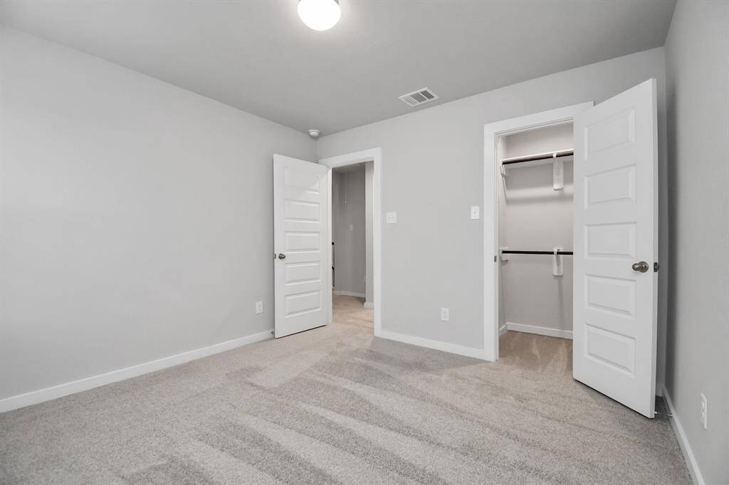 Secondary bedroom features plush carpeting, large windows that let in plenty of natural light, bright paint, and spacious closets.