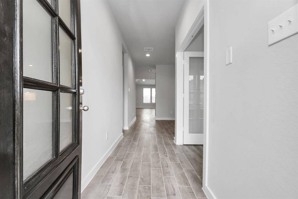 As you step into the threshold of this luxurious home, you'll soon be welcomed by an elegant glass door. Inside, soaring ceilings amplify the spaciousness, while the refined wood-look tile flooring and oversized baseboards exude sophistication and charm.