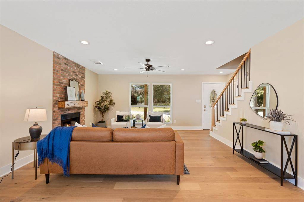 The living room features white oak wood floors, cozy fireplace, recessed lighting, and ceiling fan.