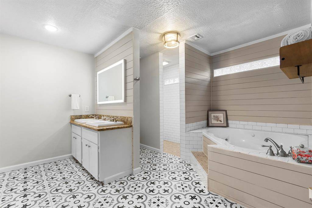 The ensuite bath downstairs has updated tile flooring and shiplap accent walls. There's a large jet tub and walk in shower that's fully tiled.