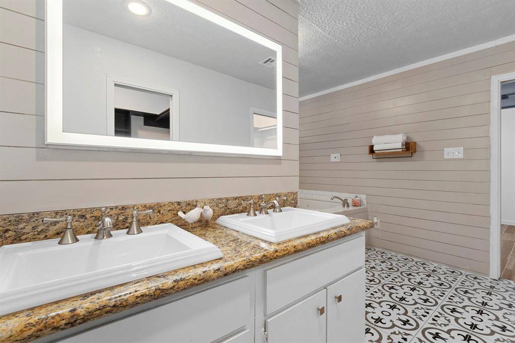 The vanity has granite counters and double sinks. The mirror is self lit.