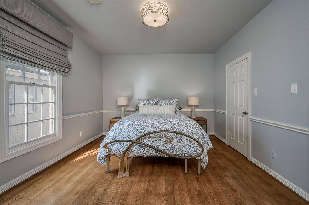 A cozy secondary bedroom featuring elegant custom Roman shades and a spacious walk-in closet.
