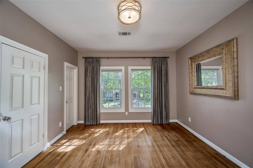 Elegant secondary bedroom with custom curtains, a walk-in closet, and treetop views. Conveniently connects to a shared Hollywood bath.