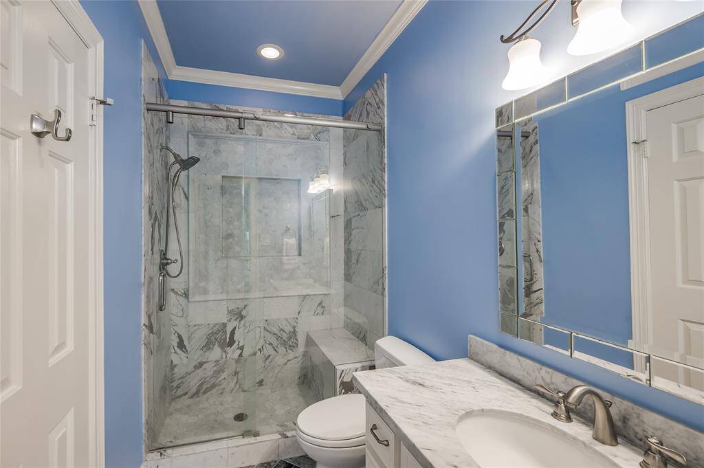 The bathroom features a sleek, seamless shower with a built-in seat. Beautiful marble vanity.