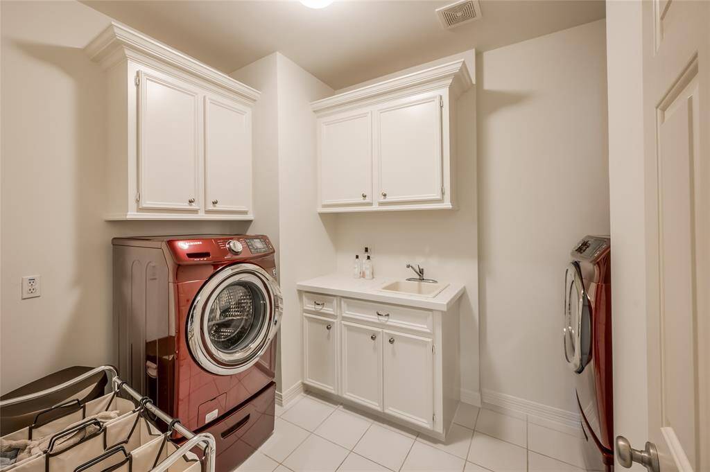 This spacious second-floor laundry room features a sink and comes complete with a Samsung washer and dryer.
