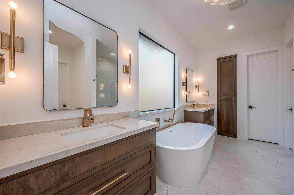 Primary bathroom- double vanity sinks with quartzite countertops, soaking tub, and double walk-in closets