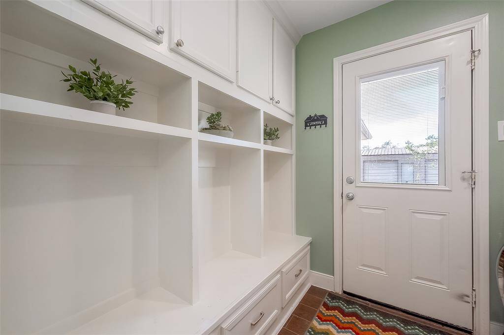 The side entry to the laundry room features a built-in drop zone offering ample storage and a bench seat.
