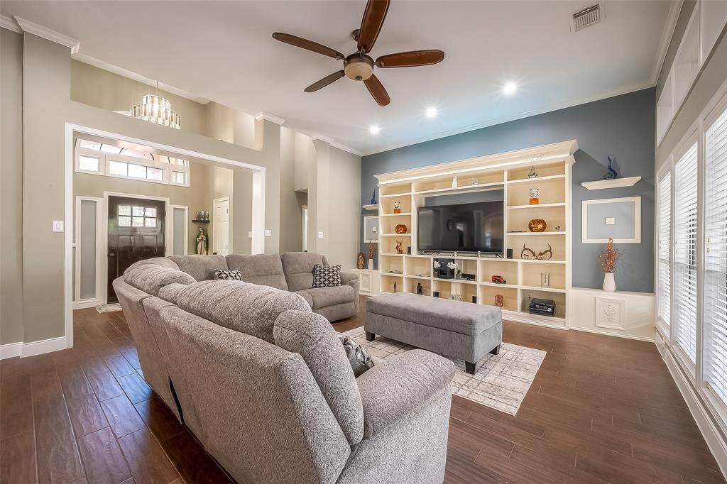 Spacious and well-lit family room with high ceilings and a large built-in entertainment center.