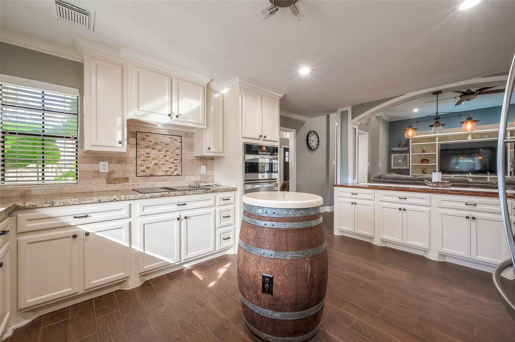 The kitchen features white cabinetry, granite countertops, and stainless steel appliances. It includes a breakfast bar with and a unique movable wine barrel that brings more prep space.