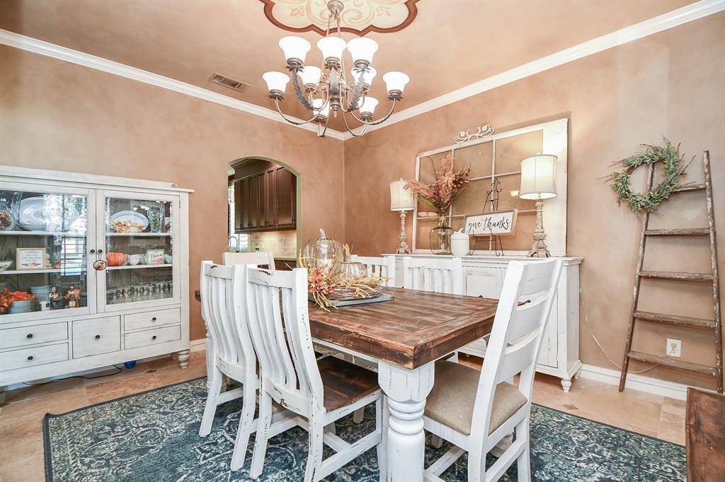 The adobe toned, mottled walls with classic crown molding add an instant rustic elegance to your formal dining space, with direct access to the chef's kitchen, left.