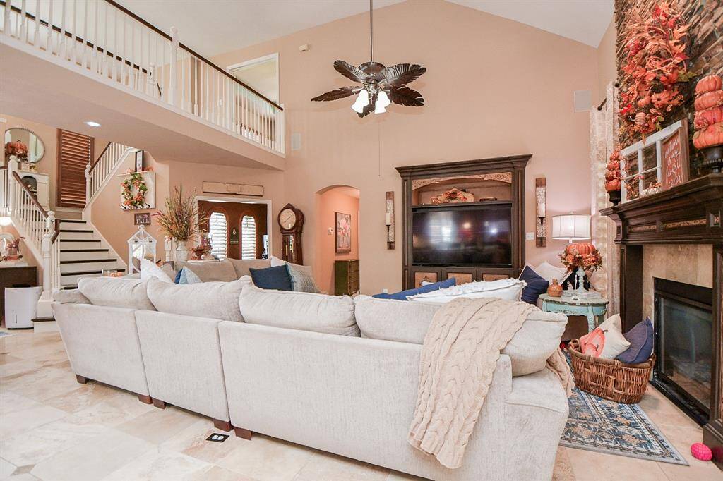 This view of your completely spectacular living/family area is nothing short of magazine worthy! The soaring ceiling hosts a gorgeous leaf accented ceiling fan, while comfy pieces of any size or shape fill this vast space. The star of the show, however, has to be the stunning built-in, stone encased, floor-to-ceiling fireplace.