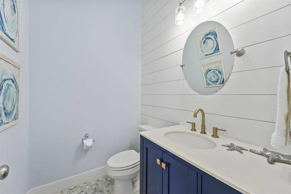 This beautifully designed halfbathroom features a bold navyvanity, shiplap accent wall, andelegant brass fixtures, providinga fresh, beach-inspired look.