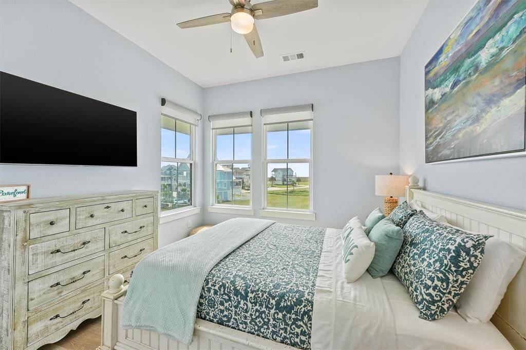 This serene guest bedroomoffers abundant natural lightthrough three large windows,showcasing relaxing views and acalming atmosphere.
