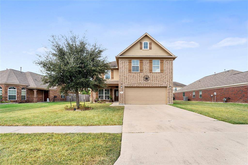 This is a two-story, single-family home featuring a brick exterior, an attached two-car garage, and a well-maintained lawn.