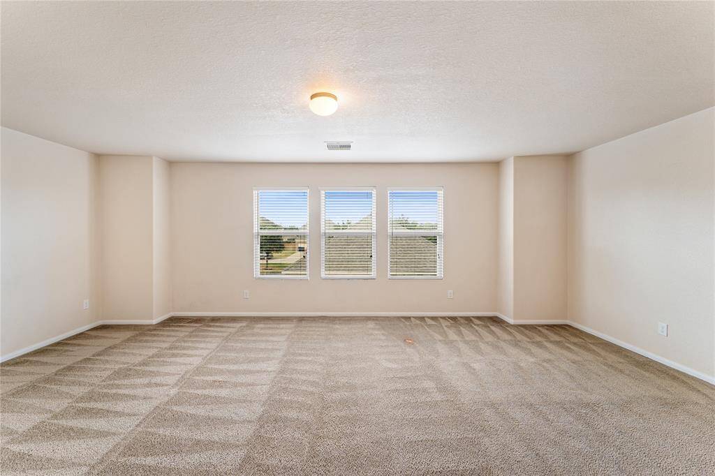 Spacious Gameroom, well-lit room with plush carpeting and a large three-panel window offering ample natural light.