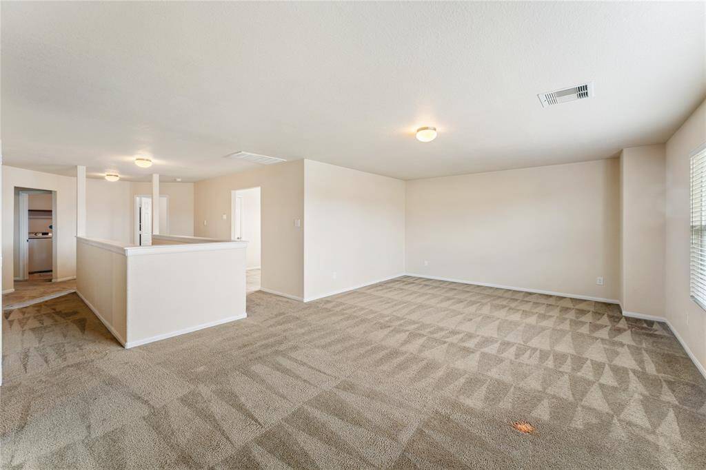 Spacious Gameroom, well-lit room with plush carpeting and a large three-panel window offering ample natural light.
