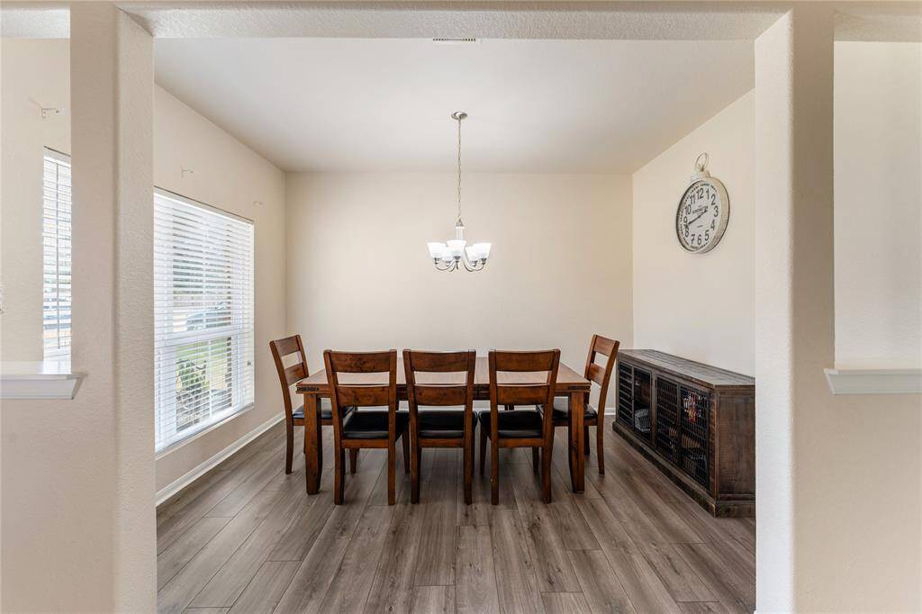 The Room Features A Neutral Color Palette With A Spacious Dining Area, And Ample Natural Light From Large Windows.