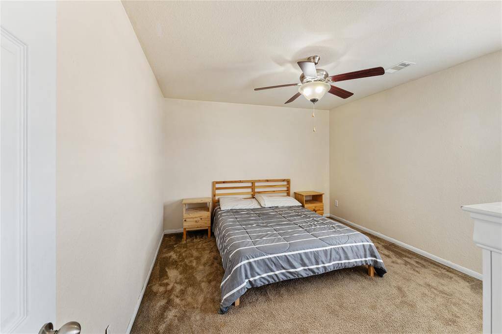 This is a well-lit, cozy bedroom featuring a ceiling fan, plush carpet.