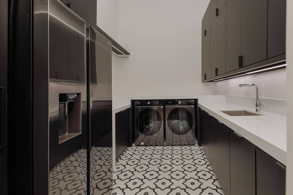 Laundry room featuring Samsung refrigeratorfreezer, washer/dryer and ample storage with dark cabinetry, a deep sink, and stylish patterned flooring.