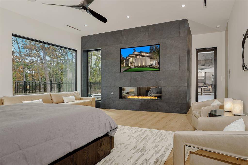 First floor primary bedroom featuring large windows with a natural view, an elegant gas fireplace and a sleek design. The space is well-lit and offers a seamless flow.