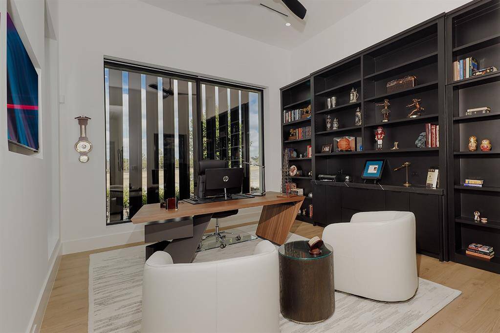 First floor office featuring a large window, extra seating and full wall built-in bookshelves.