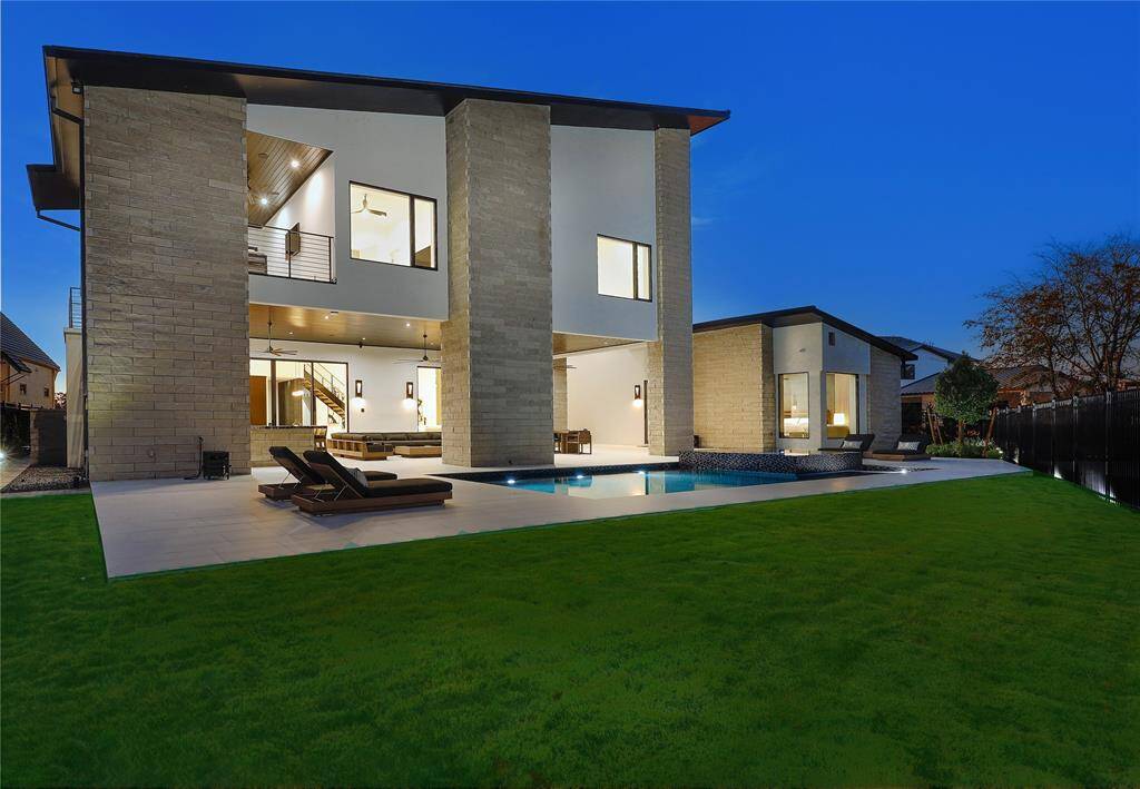Clean lines, a mix of stone and stucco exterior, large windows for natural light, and an open floor plan. It includes a well-manicured lawn and a luxurious pool/spa with adjacent lounging area, perfect for relaxation and entertainment.